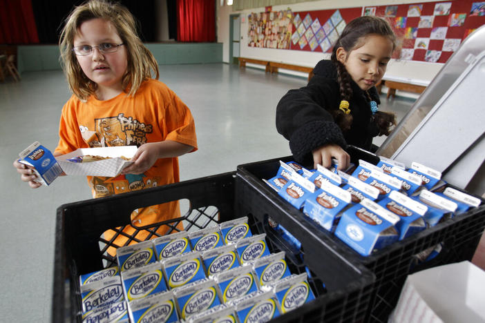 Fairmeadow Elementary School third grade students Ellery Carlson, left, and Tatiana Aboytes, right, pick chocolate milk during a school lunch program 