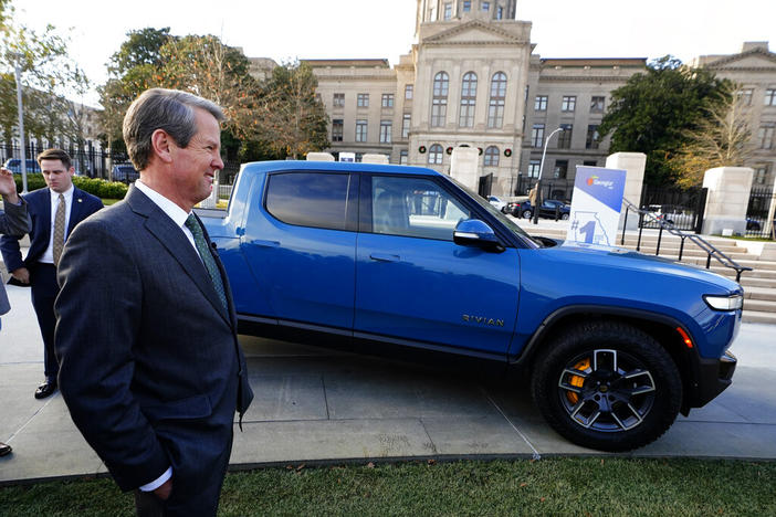 Gov. Brian Kemp stands next to a Rivian electric truck while announcing the company's plans to build a $5 billion plant east of Atlanta projected to employ 7,500 workers, Thursday, Dec. 16, 2021, in Atlanta. Some residents oppose the plant, saying it will spoil their rural quality of life.