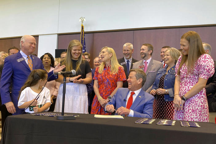 Georgia Gov. Brian Kemp laughs with state Senate President Pro Tem Butch Miller and others as he signs education bills on Thursday, April 28, 2022 in Cumming, Ga. Kemp has been using a post-session bill signing tour to enhance his position in the May 24 Republican primary for governor against former U.S. Sen. David Perdue and others.