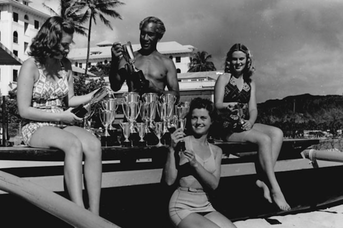 Duke Kahanamoku with his trophies and female friends.