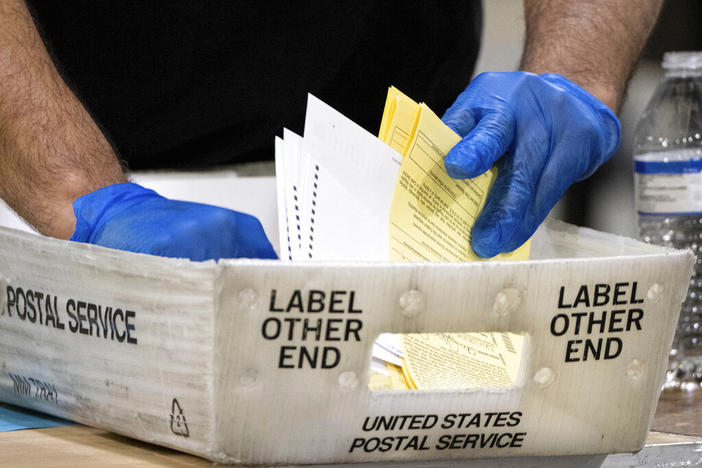 In this Jan. 5, 2021 file photo, Fulton County Georgia elections workers process absentee ballots for the Senate runoff election in Atlanta. A judge has dismissed conservative cable news channel One America News Network from a defamation lawsuit filed by two Georgia election workers after the two sides reached a settlement, Thursday, May 12, 2022.