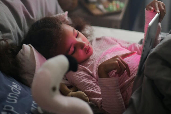 A young girl reads in bed