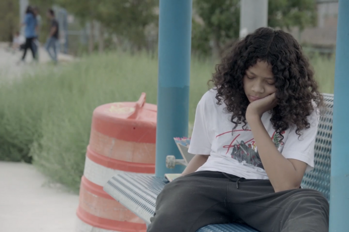 A child sits on a bench with his face in his his hand.