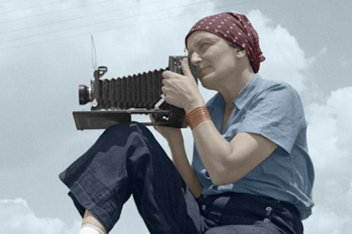An old photograph of a woman taking a picture with an antique camera.
