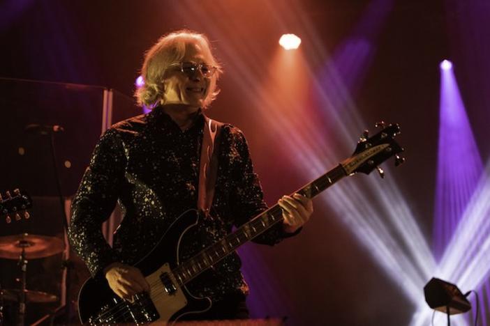 Mike Mills playing guitar on stage.