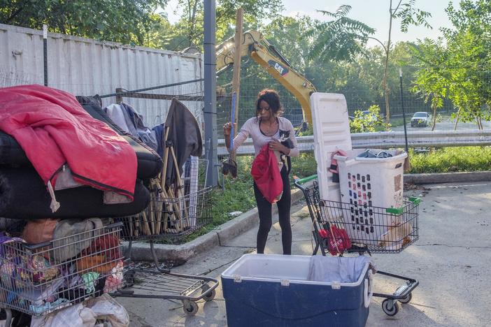 Tonithia Fernandez holds one of her two cats while also trying to pack up and move her home as a Macon-Bibb County excavator clears out another part of the encampment where she lived until Tuesday.