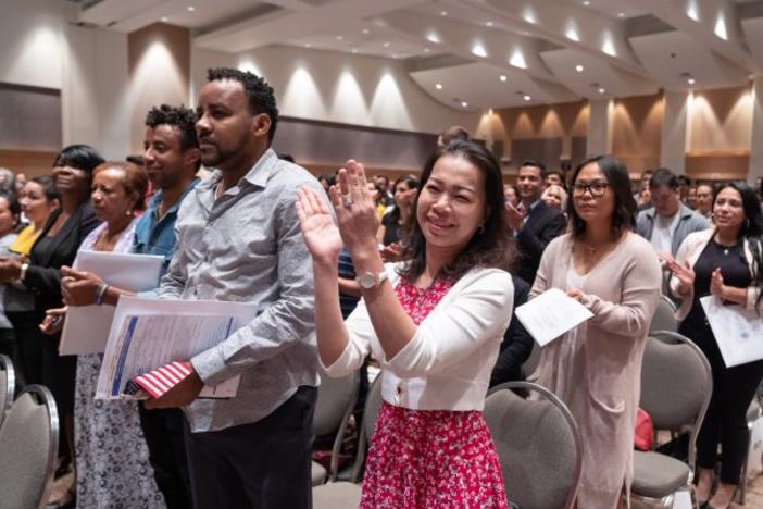 A group of new citizens claps during a naturalization ceremony.