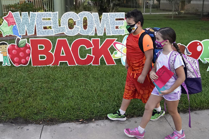 Students wearing protective masks walk past a "Welcome Back" sign before the first day of school at Sessums Elementary School Tuesday, Aug. 10, 2021, in Riverview, Fla. Students are required to wear the masks at school unless their parents opt out.