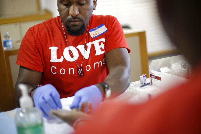 A man in gloves tests a patient for HIV