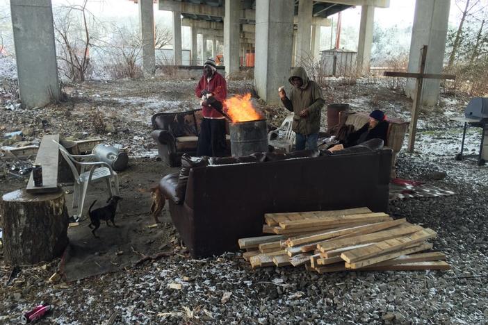 A group of people warm up around a fire at a Gainesville encampment during winter months in 2015. 