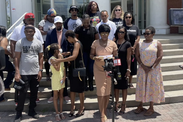 Monteria Robinson, standing before microphones assembled by local media outside of the Clayton County Police Department, is accompanied Aug. 4, 2022, by supporters of her son, Jamarion Robinson, who was killed by police in 2016.