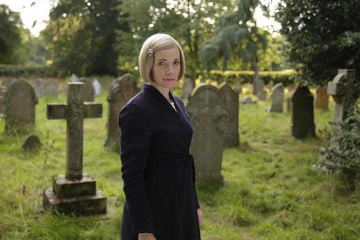 Lucy Worsley standing in an old graveyard.