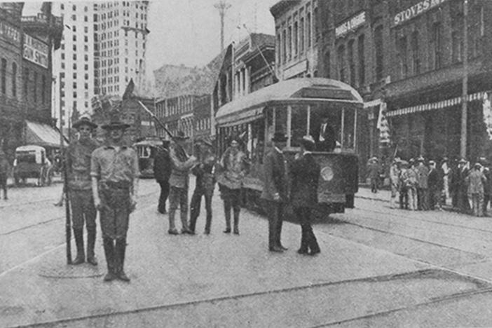 A black and white photo from 1906 shows armed militiamen patrolling the streets of downtown Atlanta.
