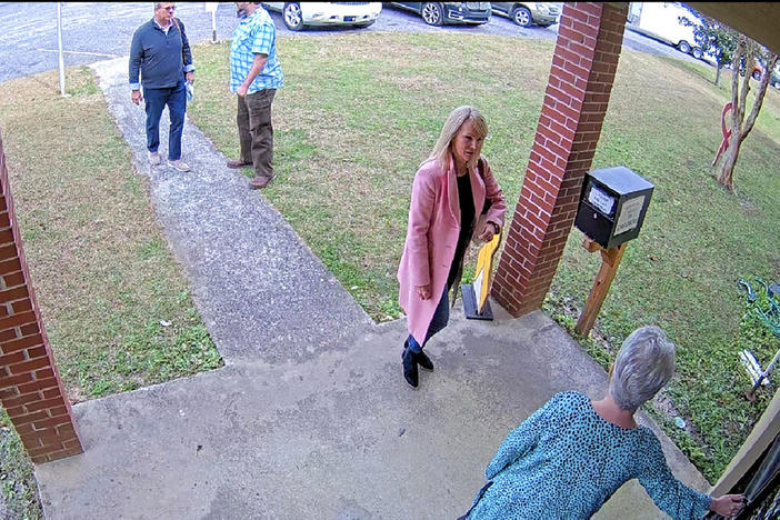 In this Jan. 19, 2021 image taken from Coffee County, Ga., security video, Cathy Latham, bottom, who was the chair of the Coffee County Republican Party at the time, greets a team of computer experts from data solutions company SullivanStrickler at the county elections office in Douglas, Ga. Records show that the team traveled to the rural south Georgia county to copy software and data from elections equipment.