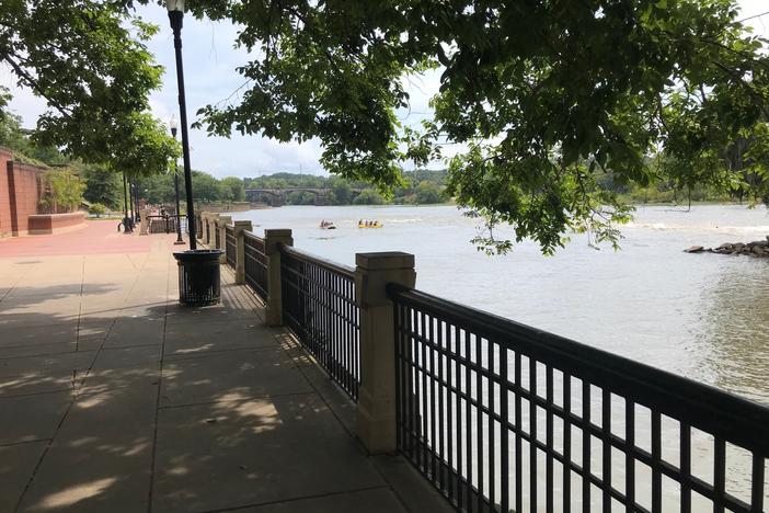 The Columbus waterfront is shown with a walkway and shady tree.