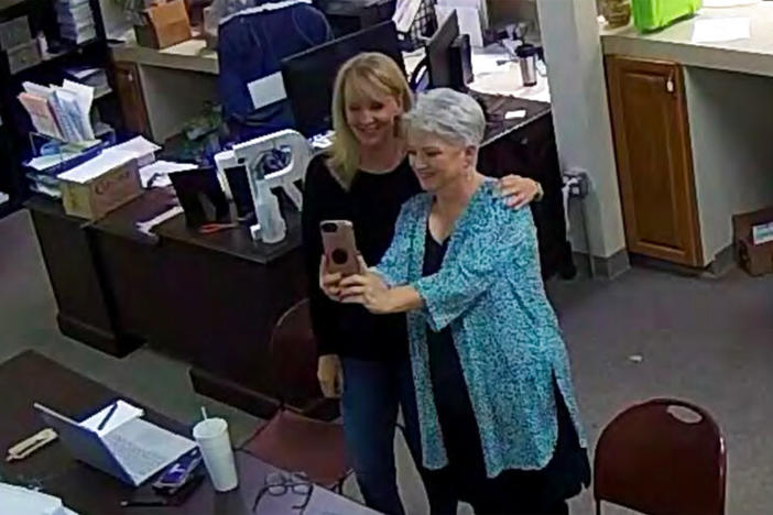 In this Jan. 7, 2021, image taken from Coffee County, Ga., security video, Cathy Latham (right) appears to take a selfie with a member of a computer forensics team inside the local elections office. Latham was the county Republican Party chair at the time. The computer forensics team was at the county elections office in Douglas, Ga., to make copies of voting equipment in an effort that documents show was arranged by Sidney Powell and others allied with then-President Donald Trump.