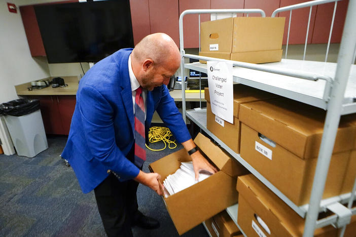 Gwinnett County elections supervisor Zach Manifold looks over boxes of voter challenges on Thursday, Sept. 15, 2022, in Lawrenceville, Ga. Manifold estimated his office has a month to log and research the challenges, before mail ballots go out for the November elections. “It is a tight window to get everything done,” he said.