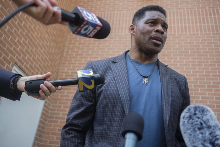 Herschel Walker talks to reporters during a campaign stop in Macon on May 18, 2022.
