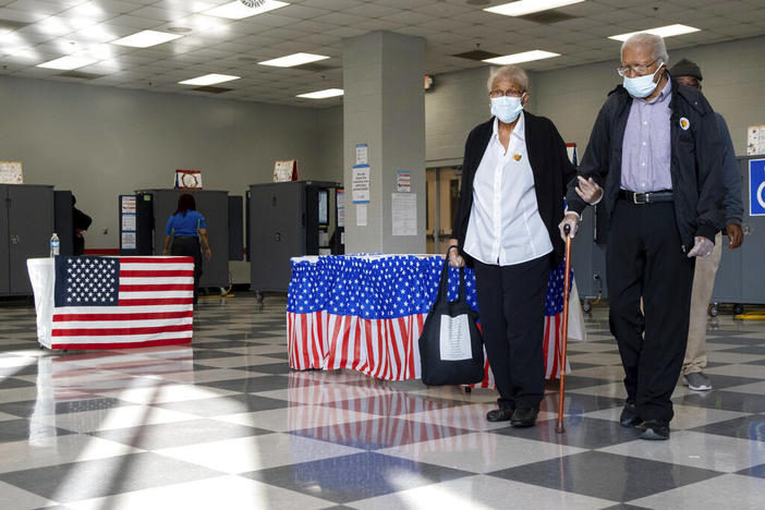 A couple leaves the polls after voting on the first day of early voting in Atlanta on Monday, Oct. 17, 2022.