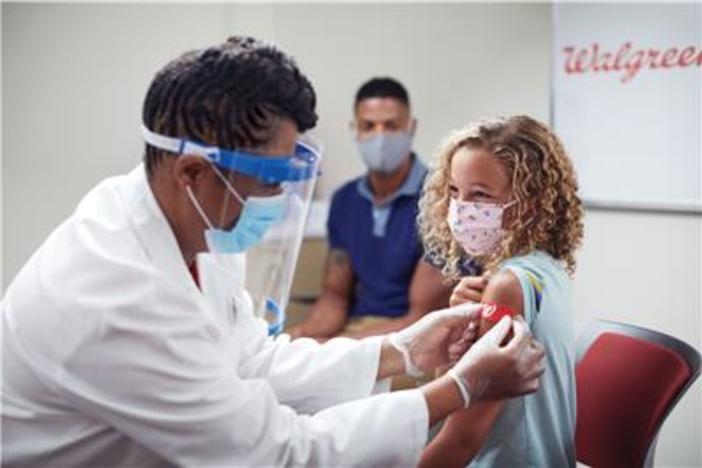 A pharmacist gives a girl a bandaid after a vaccine shot