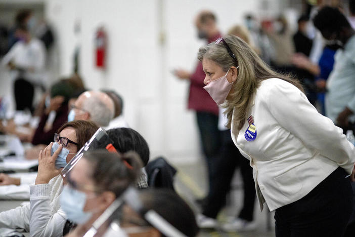 A Republican election challenger at right watches over election inspectors as they examine a ballot as votes are counted into the early morning hours, Nov. 4, 2020, at the central counting board in Detroit. Election officials across the country are bracing for a wave of confrontations in November as emboldened Republican poll watchers, many embracing former President Donald Trump's conspiracy theories about the 2020 election, flood polling places for the general election.