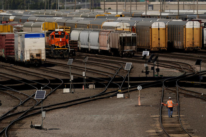A worker walks along tracks at a BNSF rail yard Sept. 14, 2022, in Kansas City. The third largest railroad union rejected its deal with freight railroads Monday, Oct. 10, 2022, renewing the possibility of a strike that could cripple the economy.