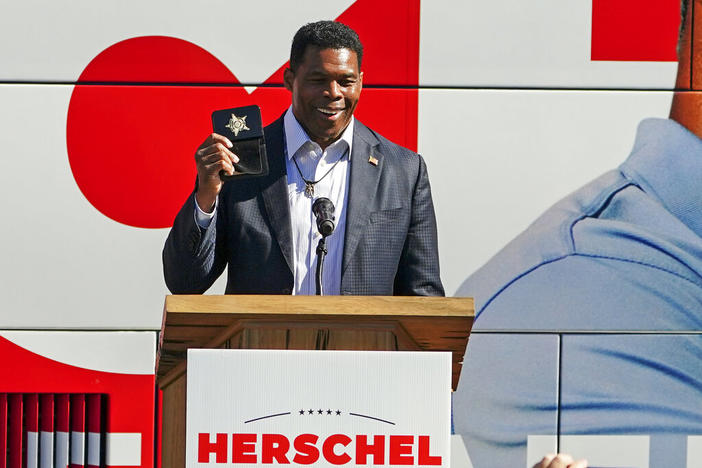 Herschel Walker, Republican candidate for U.S. Senate in Georgia, flashes a police badge as he speak to supporters during a campaign rally Oct. 18, 2022, in Atlanta.