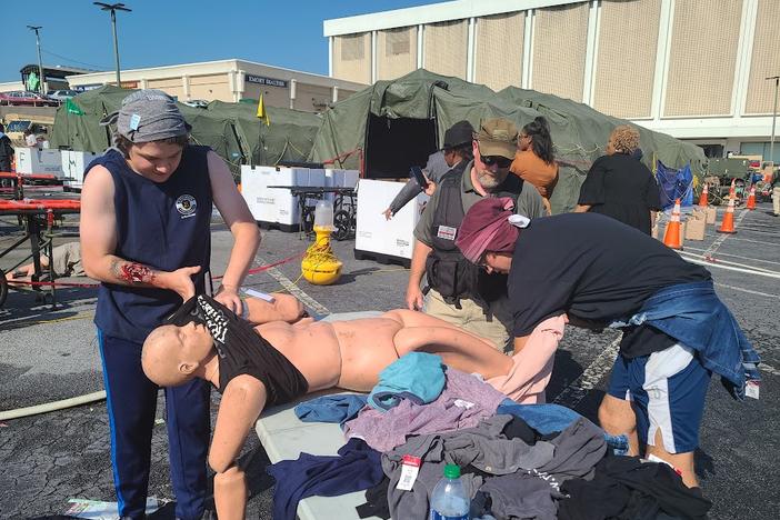 Volunteers James Baum and Ramsey Jones help to redress dummies used in the decontamination scenarios at a full scale nuclear response training in East Point, Georgia November 4, 2022.