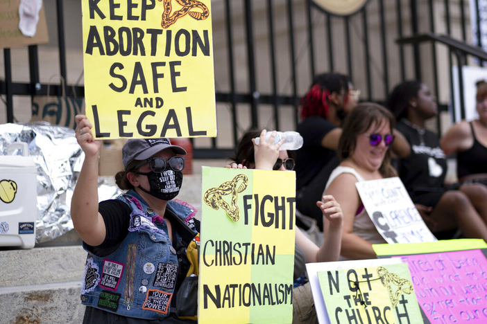 A small group, including Stephanie Batchelor, left, sits on the steps of the Georgia State Capitol protesting the overturning of Roe v. Wade on Sunday, June 26, 2022.