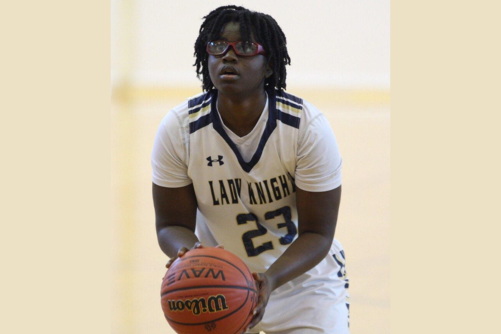 Imani Bell holds a basketball while looking upward