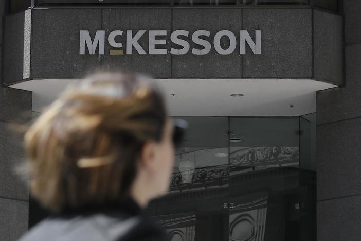 A woman with sunglasses walks in front of a McKesson building