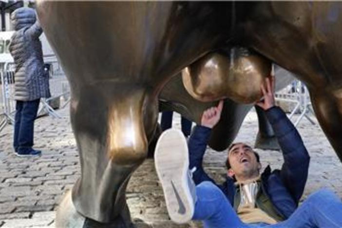 A man on his back examines the Wall Street bull statue testicles as part of a campaign to raise awareness about testicular cancer.