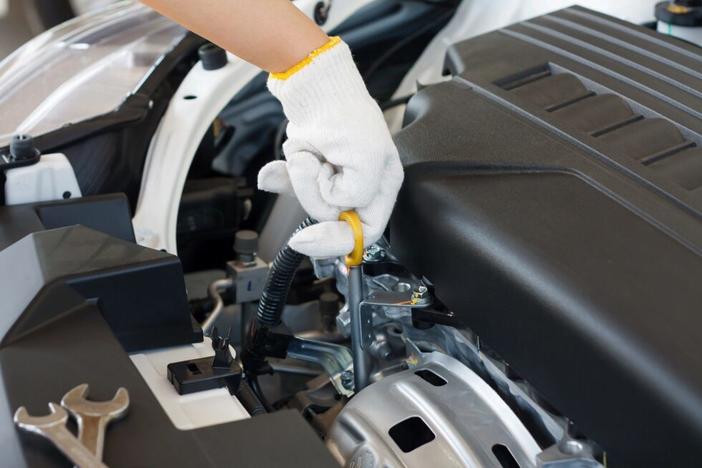 A person checks the oil in a car engine.