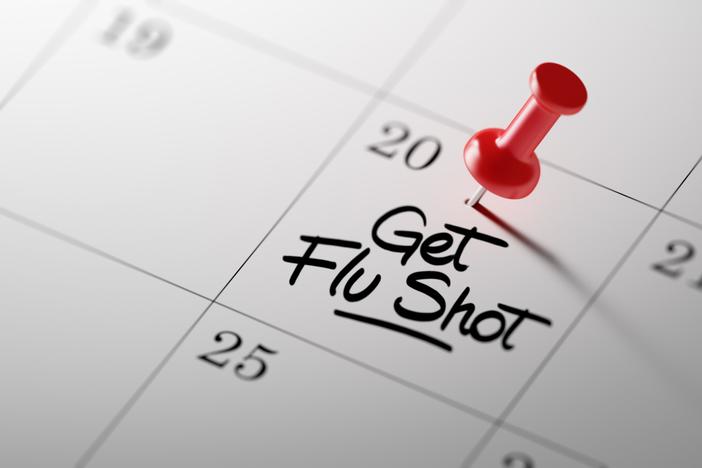 A calendar with a red thumbtack marking the date to get a flu shot