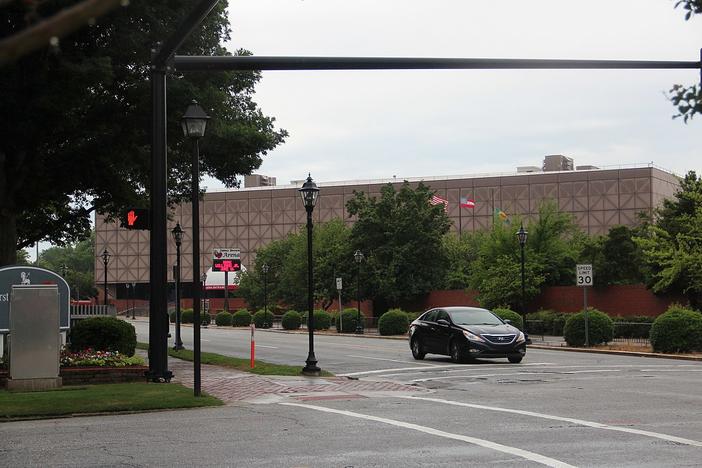 The James Brown Arena is shown in the distance behind trees and a car stopped at a traffic light.