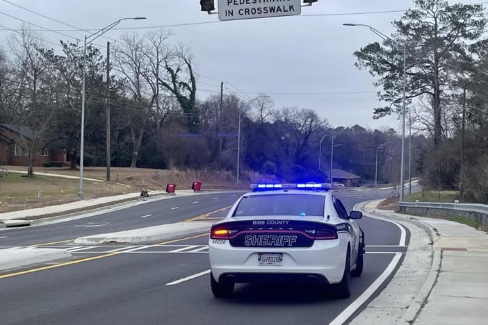 Laura Corley | The Macon Newsroom  A Bibb County sheriff deputy’s car with blue lights activated near a pedestrian crosswalk on Jeffersonville Road in Macon.