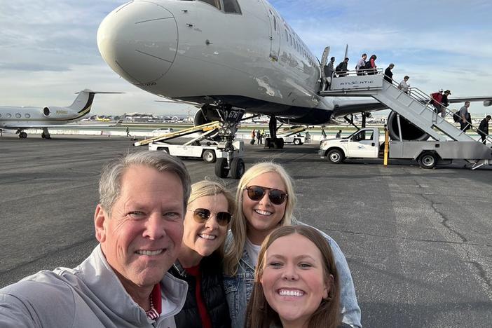 Governor Brian Kemp with family, a plane in the background.