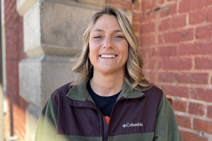 Amanda Williamson stands in front of a brick wall outside the Freight Depot