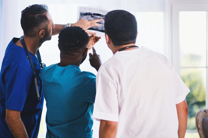 Three physicians view an x-ray.