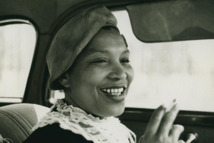 Zora Neale Hurston smoking a cigarette in a car.