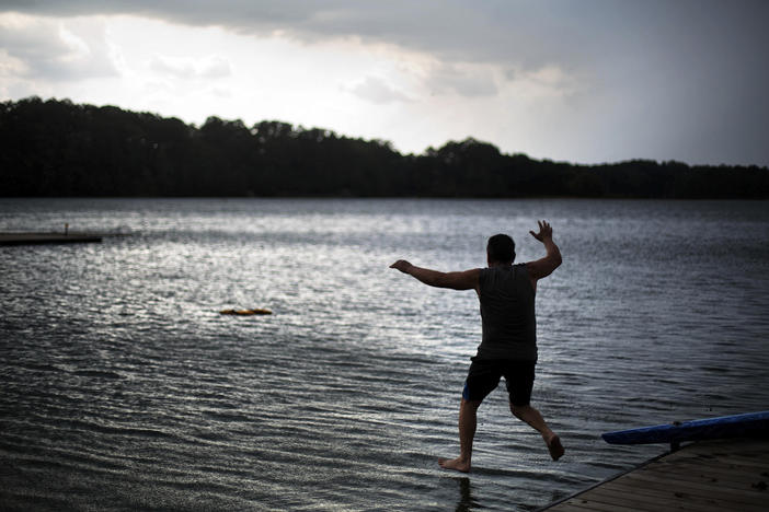 Radko Jonas jumps into the water to retrieve a life vest that blew away as rain clouds approach at Lake Lanier on July 19, 2016, in Gainesville, Ga. The U.S. Army Corps of Engineers said Friday, March 10, 2023, it is pausing a plan to rename the lake and the associated Buford Dam, both named after former Confederate soldiers, after local residents objected. 