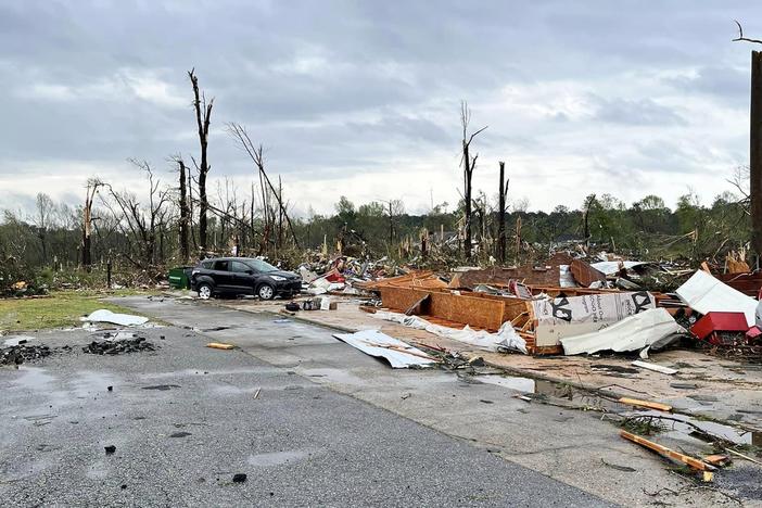 Snapped trees and destroyed homes are pictured.