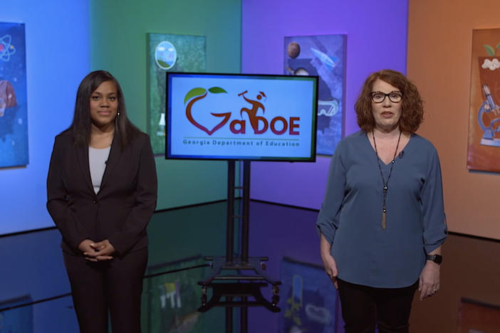 Two female teachers stand in front of colorful Science in Action set to discuss 3D Science.