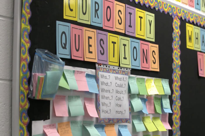 Classroom bulletin board showing 'curiosity questions' filled out by students.