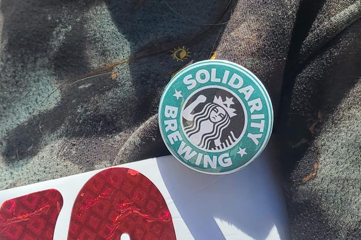 A member of the Starbucks Workers union wears a "solidarity brewing" pin at a rally for improved working conditions on May 1, 2023.