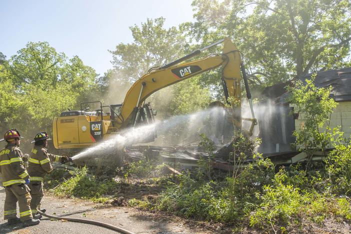 Firefighters spray a house in mid-demolition to keep dust down during the destruction of the 500th blighted structure in two years in Macon Tuesday. 