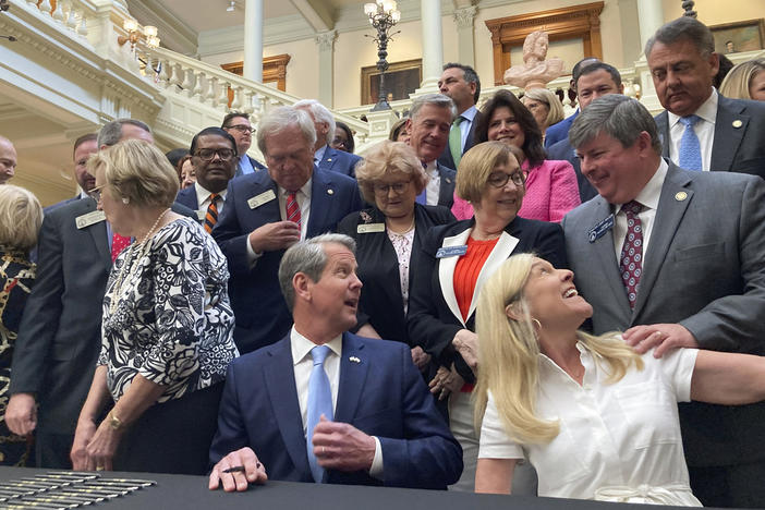 Georgia Gov. Brian Kemp, bottom center, speaks to state Sen. Larry Walker III, R-Perry, right, before signing bills into law at the state Capitol on Tuesday, May 2, 2023, in Atlanta. Georgia's state government will for the first time run its own marketplace for individual health insurance under a law that Republican Gov. Kemp signed. 