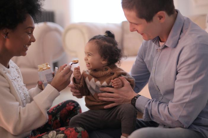 A couple feeds a young child peanut butter