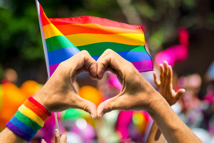 Love symbol with hands in front of a pride flag