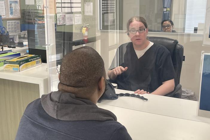 Justin Howell sits behind glass at the intake window at the Behavioral Health Crisis Center in Athens, Georgia.